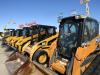 An assembly of skid steers shines brightly in the hot desert sun.
