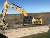 A Caterpillar 325 marsh excavator is used to move pipeline in the disposal area.