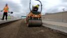 Using a roller, the ground is being compacted for a new section of road.