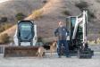 Facilities Manager Jim Wiggins and one of the canine participants take a break with a Bobcat CTL and excavator.