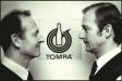 TOMRA founders Petter and Tore Planke standing in front of original TOMRA logo.