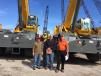 (L-R): Joe Villa, Ransome CAT; Greg Barwis, James J. Anderson Construction, Philadelphia, Pa.; and Joe Boyle of Ritchie Bros. stand in front of two Grove RT880E cranes that will be heading to James J. Anderson Construction job sites.