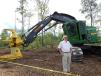 Tim J. Murphy, president and CEO of Nortrax Inc., stands with a John Deere 853M tracked feller buncher.  
 