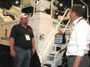Talking about the addition of steps (rather than ladders) and a crossover platform incorporated into the unique design of the brand new Roadtec, the MTV-1100e material transfer vehicle, are Bryan Ady (L), Goodfellow Corporation, Boulder City, Nev., and Roadtec Product Manager Kyle Neisen. 