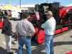 Frank Plotts (L) of Fecon, based in Lebanon, Ohio, discusses the centerpiece of the Fecon display, a Fecon FTX128L high performance prime mover.
 