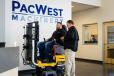 PacWest open house guest, Eric Rice, tests his skills on the Volvo excavator simulator machine with instructions from Volvo CE representative Dave Adams. 
