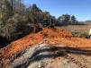 The operator of a Cat 308C excavator rebuilds a dam that was washed out during the floods in South Carolina.