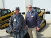 Randy Ritola (L) of Ritola Inc. asks Loren Lagesse, Fabick Cat, questions about this Caterpillar 239D equipped with a Cat LR18B rock rake.
