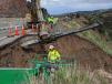 Contractor crews place a large drill that places reinforcing steel bars under the roadway to stabilize the slope that was washed out.
(CDOT photo) 