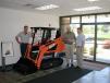 The original 1979 Takeuchi tracked machine is flanked (L-R) by Nick Grittani, Northeast factory representative of Takeuchi; Clay Eubanks, president of Takeuchi; and Gary Wade, president of All Island Equipment.  