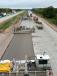 The concrete runs through three machines: the paving machine, then the carpet drag (creating texture) and the curing machine (this sprays cure on the surface).
   (Photo courtesy of MnDOT)