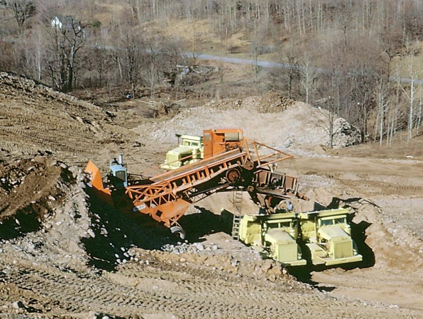 Lane Construction photo
One of the four Kolman belt loaders is seen in this circa 1962 photo. The oversize material not suitable for use in the dam is being scalped by a screen. The haul trucks are Euclid R-27 end dumps.