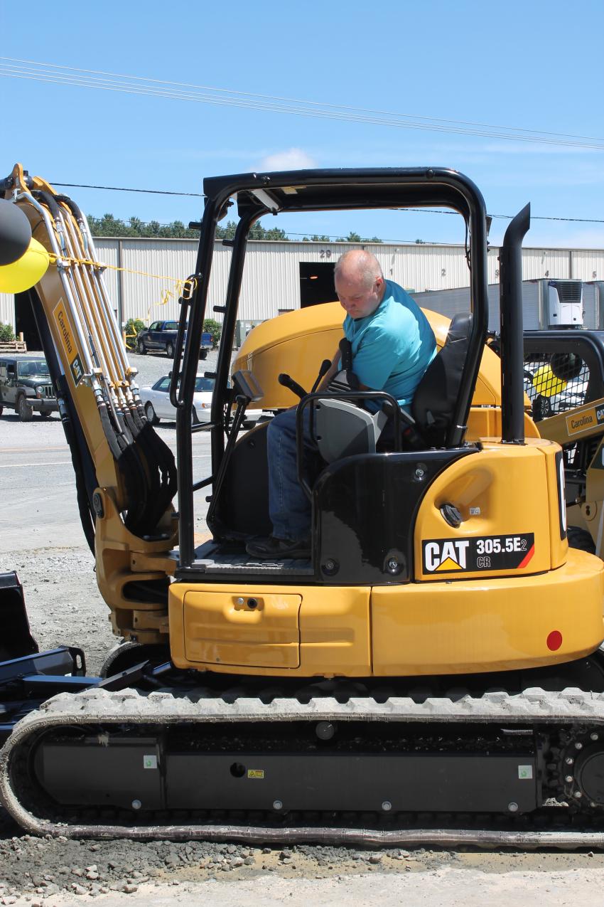 A guest thoroughly inspects the 305.5E2 mini-excavator. 
