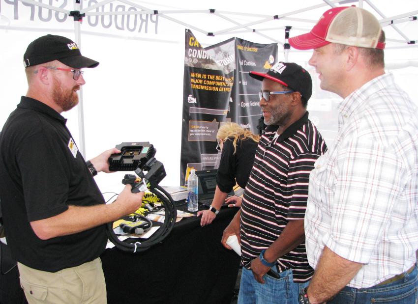 Mike Kable (L) and Sean Courtney (R) of Yancey Bros. talk with Rob Stone of Site Engineering, Atlanta, Ga., about the hardware behind the Cat VisionLink system, which functions similarly to a “black box” in an airplane.  
