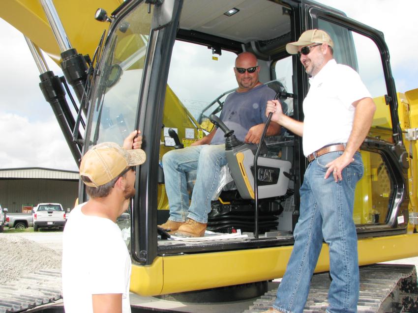 Caleb Asher (L) and Paul Asher (in cab) of Dekalb Pipeline, Conyers, Ga., have a Q & A session on the new excavators with Caterpillar’s Andrew Cardinal.  
