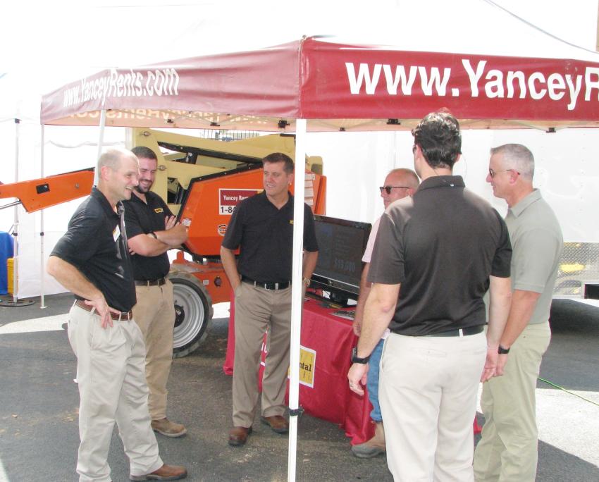 Guests grab a bit of shade under the Yancey Rents display tent in between test operation of some of the machines being showcased. 
