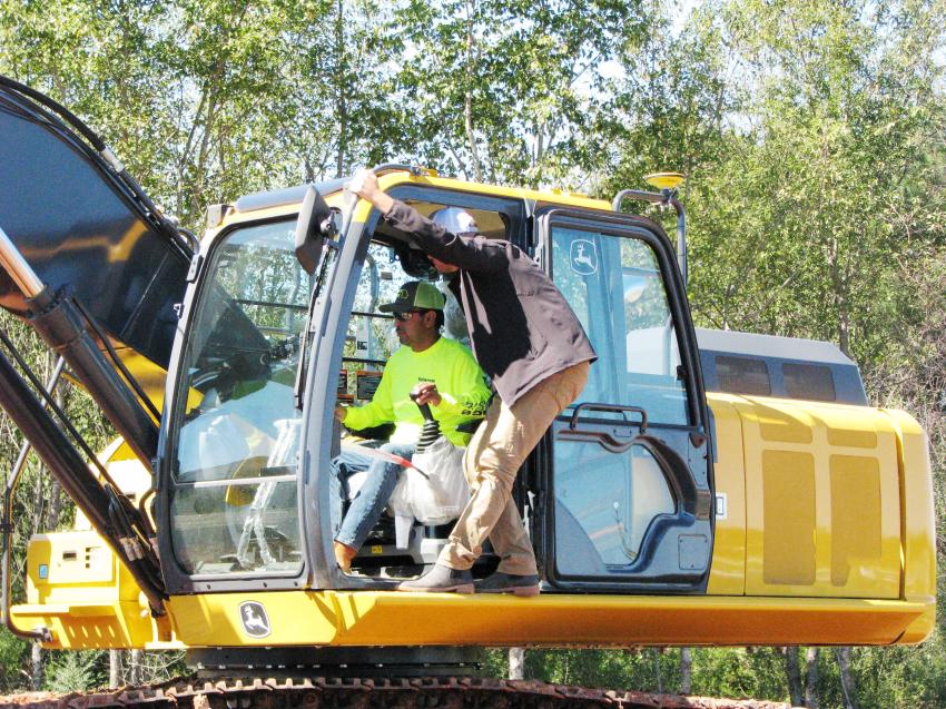 Test operating a Deere 210G with a Leica ICON 3D dual mast excavator machine control system is Antonio Juarec of Balance Site Inc., Suwanee, Ga. (L) with some pointers from Construction Laser’s Jay Allen. 
