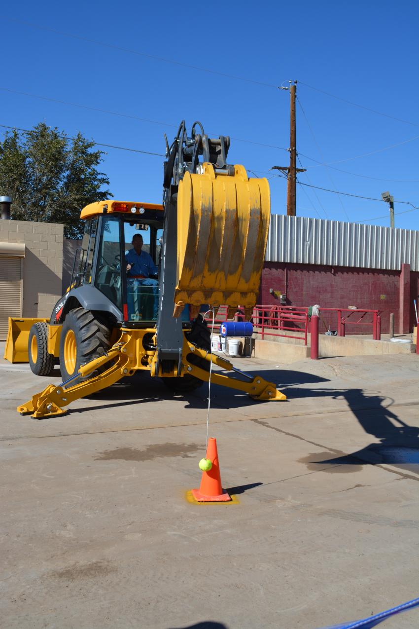 A 4Rivers customer operating a John Deere backhoe loader attempts to place a tennis ball on a traffic cone during one of the skill games.
