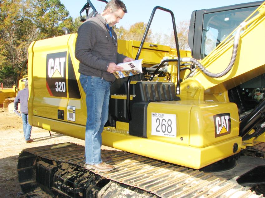 Brian Burns of Puckett Machinery-Cat, Jackson, Miss., reads up on a real gem in the sale, a virtually brand-new 2018 Cat 320 with only 23 hours on the meter. 