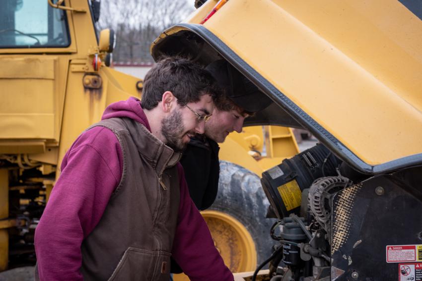Cameron Clark (L) and Josh Upton of Cams Lawn Care and Landscape LLC in Houlton, Maine, check out the engine of a 2007 John Deere 304 J wheel loader.
