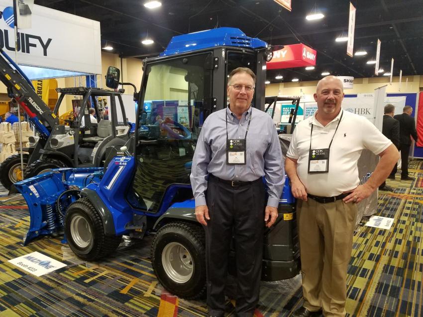 At the MultiOne booth, Bill Grundy (L), national sales manager, and Doug Campbell, operations manager, stand beside the MultiOne 8.4S.
