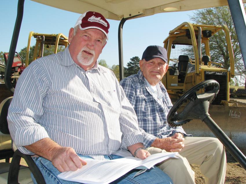 Kenny Dodd (L) and his dad, Dean Dodd of D & D Sales, Winfield, Ala., cruise the auction site by golf cart looking for the machines they plan to bid on. 

