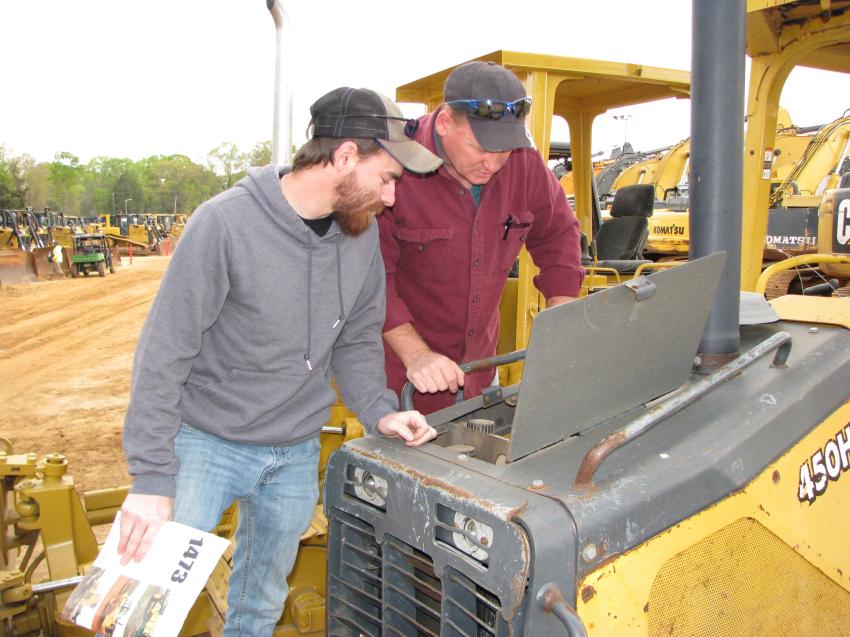 Checking under the hood of a John Deere 450H crawler tractor are first-time J.M. Wood auction attendees James (L) and Jay Shaffer of JIT Transport, Johnstown, Pa.
