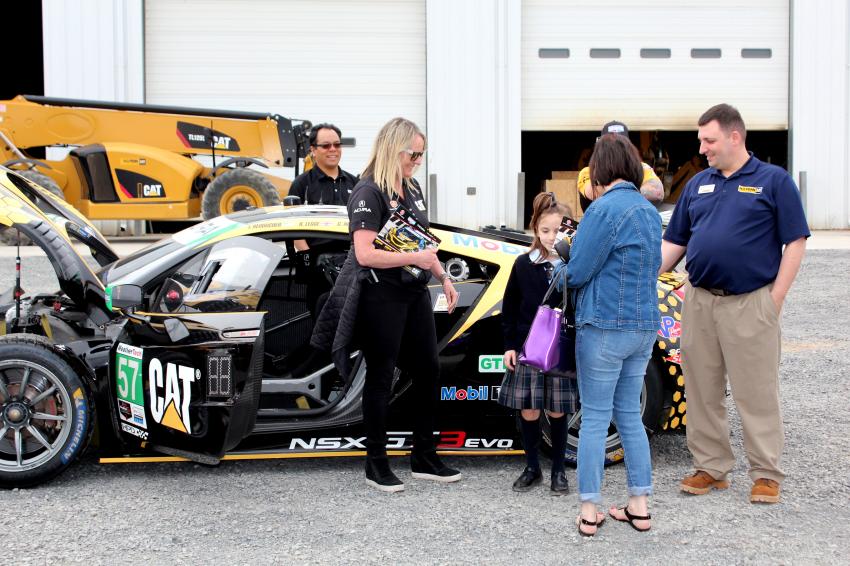 Jackie Heinricher, driver of the Cat IMSA racecar, entertains a young fan.