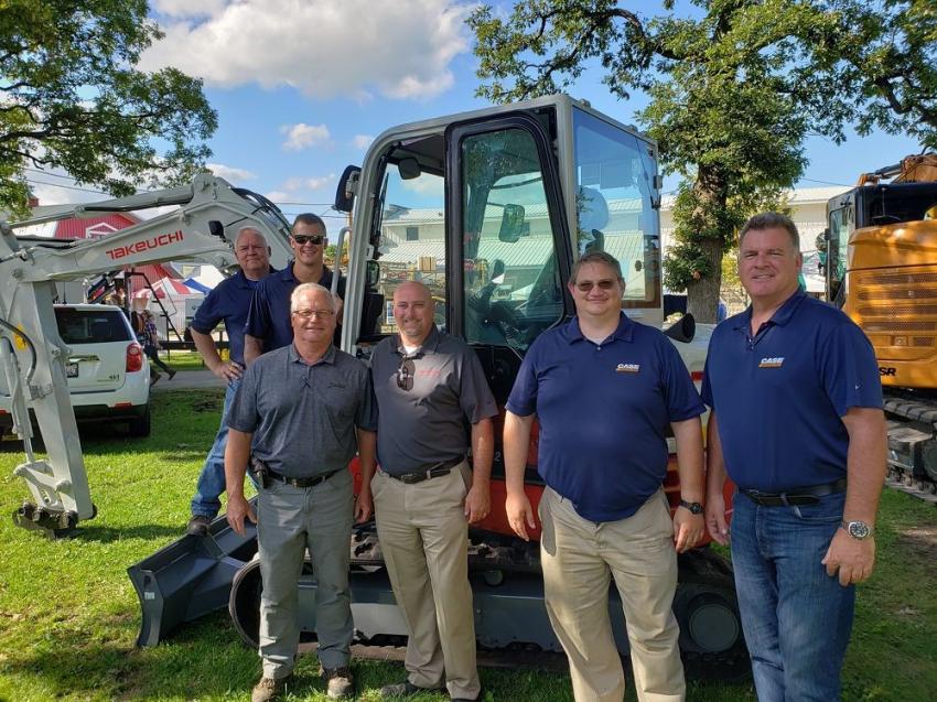 In front of a Takeuchi TB250-2 at the McCann Industries display area (L-R) are Ray Sullivan of McCann Industries; Ryan Carr of McCann Industries; Steve Costello of McCann Industries; Paul Wade, regional business manager of Takeuchi; and JR Boerner and Ken Schmidt, both of McCann Industries.