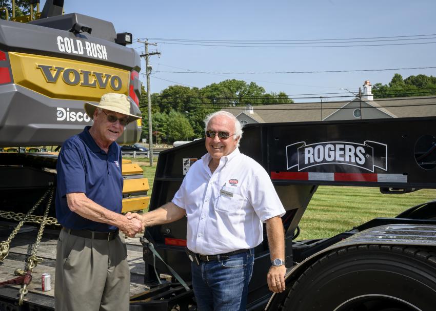Jon Grant (L), municipal sales of Tyler Equipment, and Mike Flynn of Rogers in front of the 3-axle 110,000-lb. capacity front load trailer, which is carrying the Gold Rush excavator around the country.