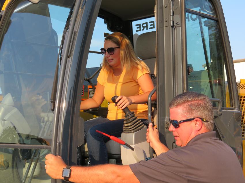 Eric Eichner (R) of Erb Equipment Co. goes over the controls of this John Deere 135G excavator with Nicole Geiger of S.M. Wilson and Co.
