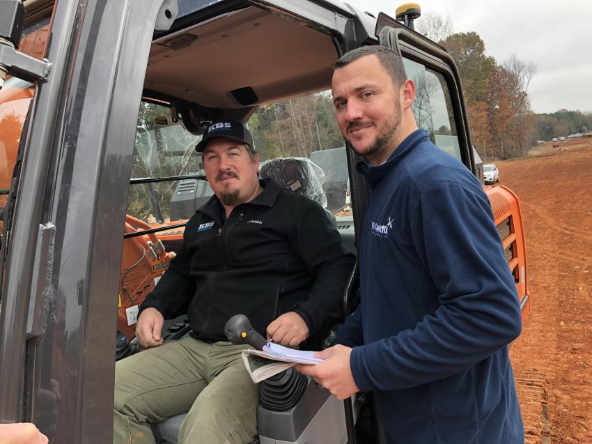 Kory Strader (seated) of KBS Earthworks in Julian, N.C., listens to Thomas Ethridge of Benchmark as he goes through how to use the X-53x Topcon system on the Hitachi excavator.
