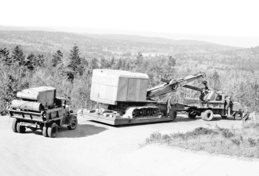 In Maine — A Thew Lorain 75 shovel is on a Rogers trailer headed down Cadillac Mountain in Acadia National Park, Maine, in the 1930s. The single axle dump trucks appear to be Internationals. The one in the rear is loaded with an air compressor for traction. It is chained to the trailer to add braking force on the steep decline. The shovel is owned by Green & Wilson of Waterville, Maine.
(Maine DOT photo)