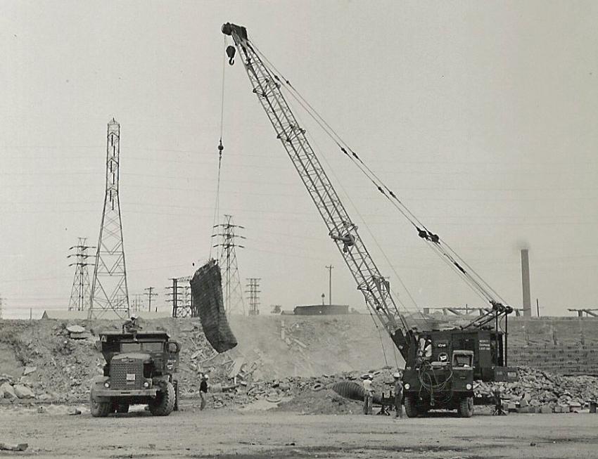 On August 15, 1959, sixty years ago, Merritt-Chapman & Scott is using a Marion 43-M truck crane to pick a blasting mat during construction of the Niagara Power Project. The hauler is one of some 120 R22 and R27 Euclids and PH95 Payhaulers M-C&S massed to handle nearly 17 million yds. of rock excavation on two contracts to construct the power plant, intake structure and two conduits. The mat is placed over a small blast to contain debris.
(Marion Power Shovel Company photo, HCEA Archives)