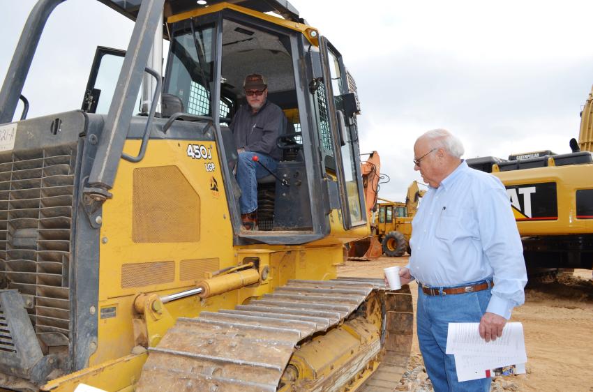 Bill Mitchell (in cab) and Gene Taylor of Warrior Tractor discuss the condition of a John Deere 450J dozer on construction equipment sale day.