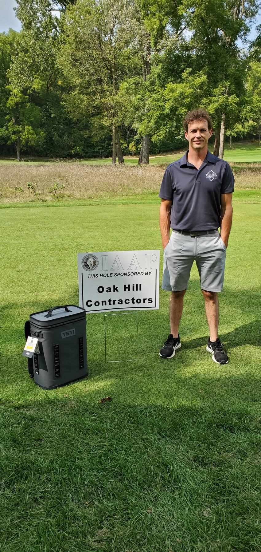 Oak Hill Contractors hosted a longest drive contest on hole #13 with a Yeti cooler going to the winner and cinch bags and tumblers for each golfer. Ben Cox of Oak Hill Contractors watches over the contest.
