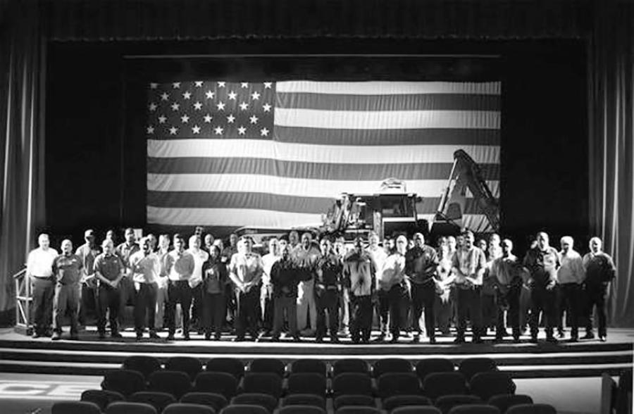JCB honors employees who served in the military at a ceremony. Behind the 70 employees is the JCB HMEE, built in the Savannah facility for military use.