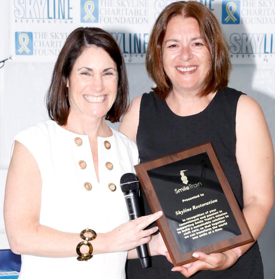 (L-R) Smile Train CEO Susannah Schaefer presents congratulatory plaque to Eva Hatzaki, Skyline Restoration Director of Marketing, at Skyline’s Eighth Annual Golf Classic which has raised close to 400K for Smile Train since 2009. Credit: George Constantinou Photography.