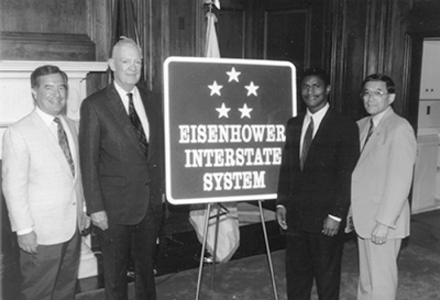 The road sign for the Dwight D. Eisenhower National System of Interstate and Defense Highways, designed by FHWA and the American Association of State Highway and Transportation Officials, was unveiled in a ceremony on Capitol Hill on 7/29/93. Left to right: Chairman Nick J. Rahall (D-WV) of the House Surface Transportation Subcommittee, John Eisenhower,  Federal Highway Administrator Rodney E. Slater, and Chairman Norman Y. Mineta (D-CA) of the House Committee on Public Works and Transportation.