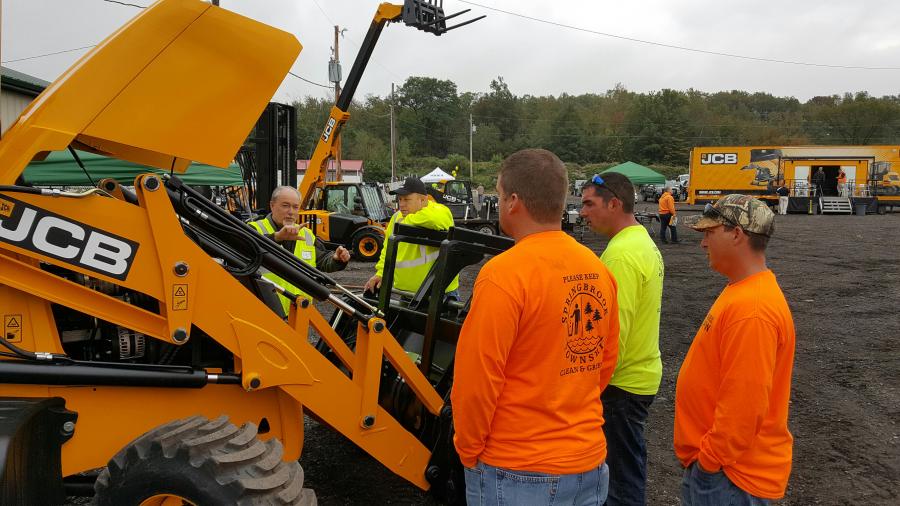 JCB representative Bob Fuend talks with crews from Springbrook Township about the easy accessibility for maintenance on the JCB 3CX backhoe.