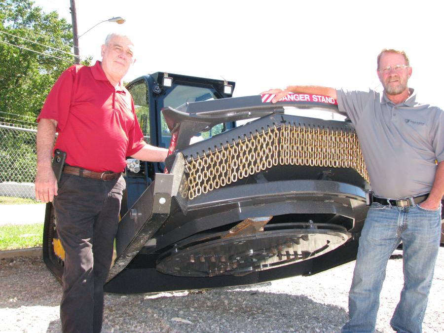 Jim Myers (L) and Marty Owen, both of Paladin, answer questions about the selection of skid steer and compact track loader attachments on display, including this Paladin-Bradco Ground Shark heavy-duty brush cutter.