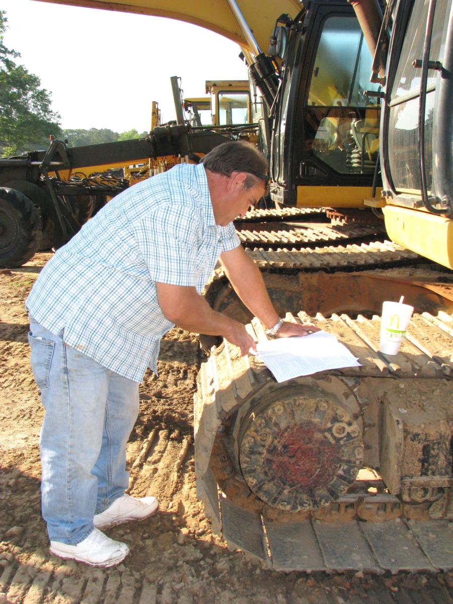 Jeff Stewart of J & S Farms, Toccoa, Ga., reads up on the excavators listed in the bidder’s catalogue.