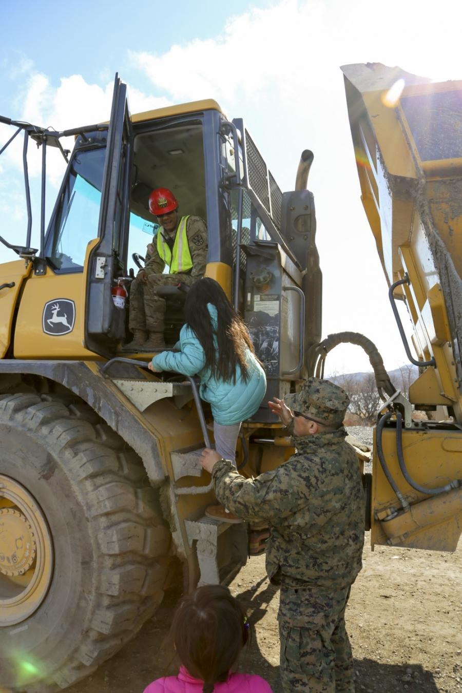 Chief Warrant Officer 3 Jason Garcia, a project coordinator for Innovative Readiness Training Old Harbor, who is with the Marine Corps Wing Support Squadron 471st Marine Aircraft Wing, U.S. Marine Corps Forces Reserve, loads a local school student into a rock truck driven by an Arizona National Guardsman from the 259th Engineer Platoon during their visit to the Innovative Readiness Training runway extension project at Old Harbor, Alaska.
(Staff Sgt. Balinda O’Neal Dresel photo)