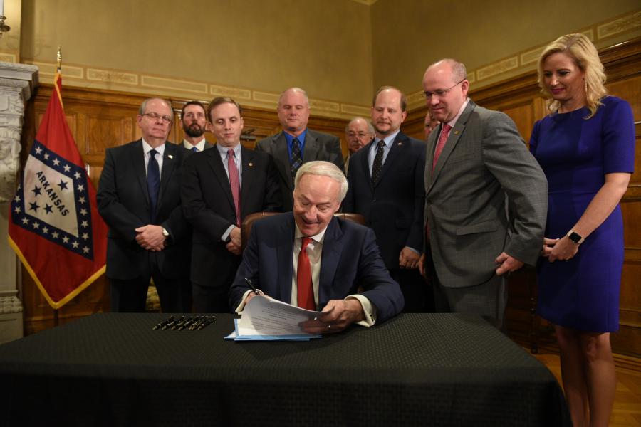 Arkansas Gov. Asa Hutchinson signs into law key pieces of a new two-part, $300 million highway-funding plan for the state.