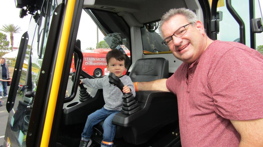 Kane, with a little guidance from his grandfather, Larry, gets behind the wheel of a JCB Teleskid 3TS-8T donated by Southwest JCB.
