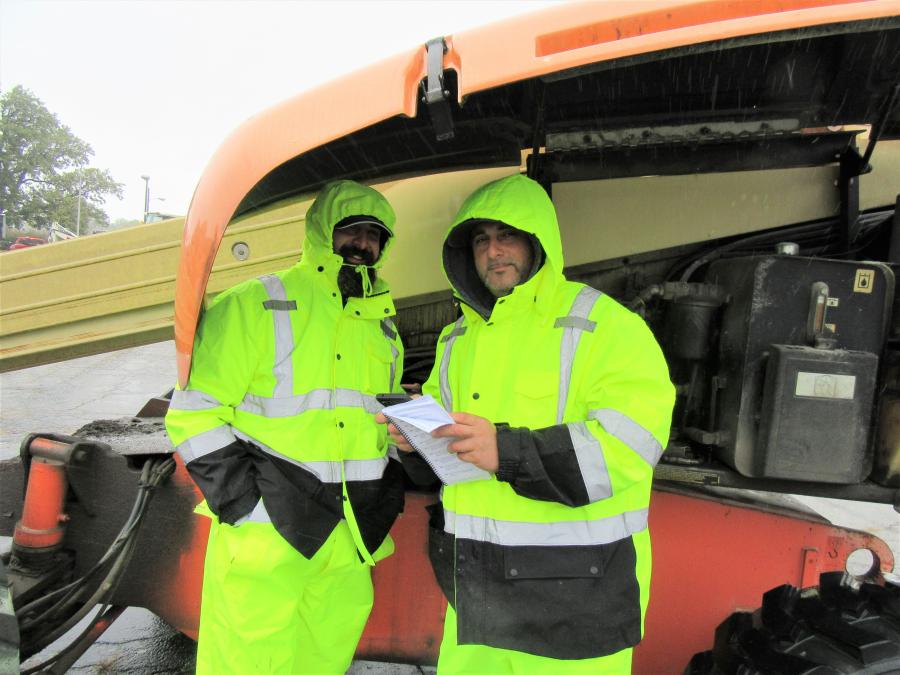 Tony (L) and Moe Shaban of Shaban Construction found shelter from the rain under the hood of this JLG telehandler.
