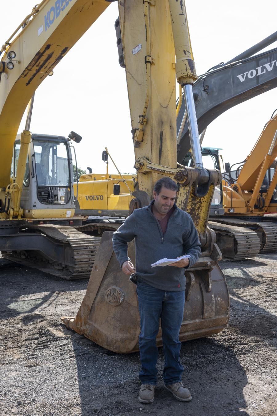 Ben Moreira of Cardi Corp. in Warwick, R.I., checks out the detailed auction catalog in front of a 2003 Kobelco SK290LC hydraulic excavator.