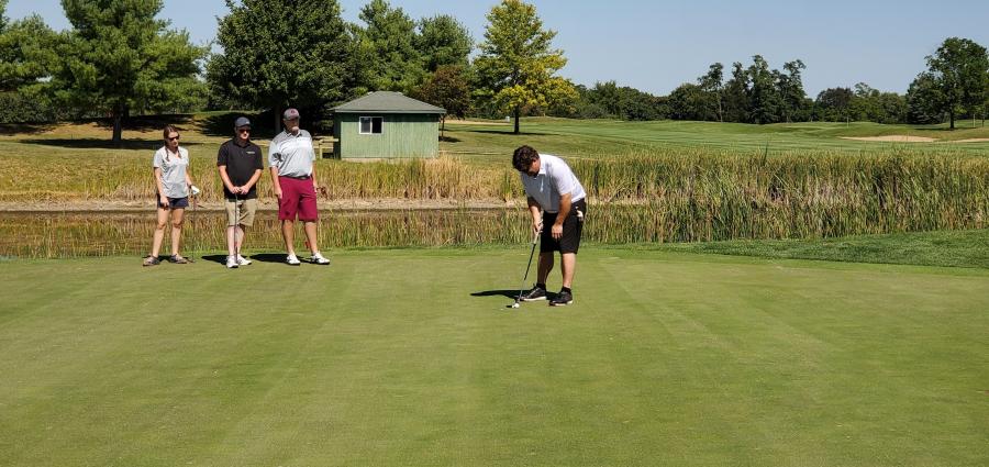 Mark Rademaker (R) of American Bin & Conveyor lines up a putt while (L-R) Erin Van Brooker of Bowser Morner Testing Laboratory; Ben Hornsey of Hanson Material Service; and Hamilton White of Turnkey Processing Solutions look on.