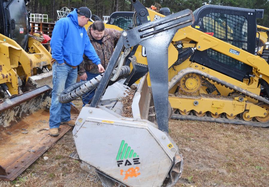 Looking over some of the attachments available, including this FAE skid steer mulching head attachment, are Justin Crawford (L) and Michael Coggins of B&B Specialized Hauling, Buchanan, Ga.