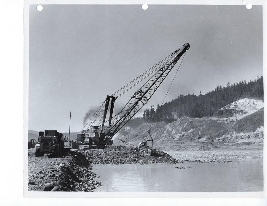 Circa 1960, a Manitowoc 4600 dragline is loading Euclid bottom dumps during construction of Hills Creek Dam in Oregon. A joint venture of Green Construction Company and Tecon Corporation is doing the work. 
(Manitowoc Company photo/HCEA)